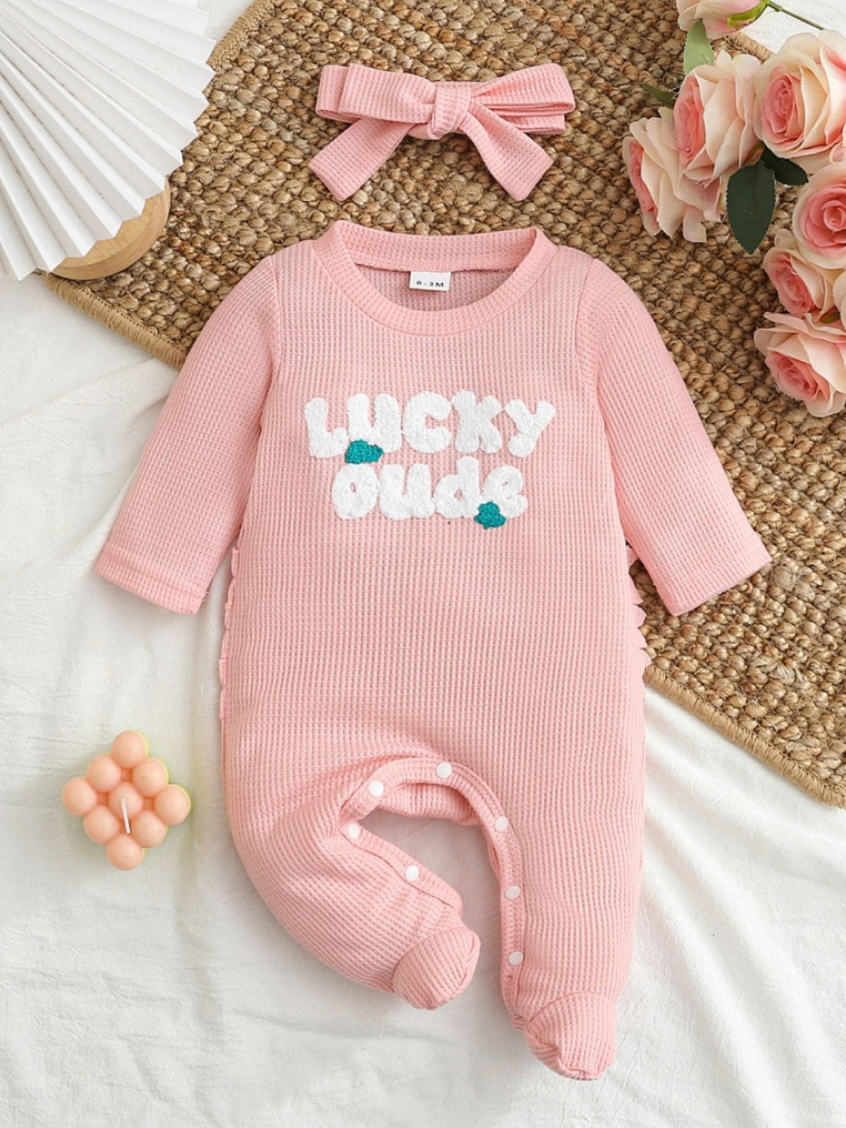 Pink waffle knit baby one-piece with "Lucky Buds" applique and matching headband.