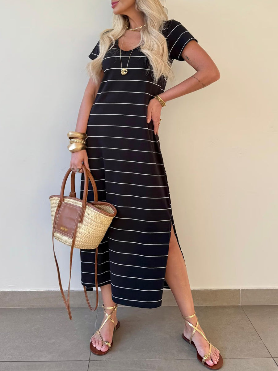 Black and white striped midi t-shirt dress with short sleeves and side slits, styled with sandals and a straw bag.