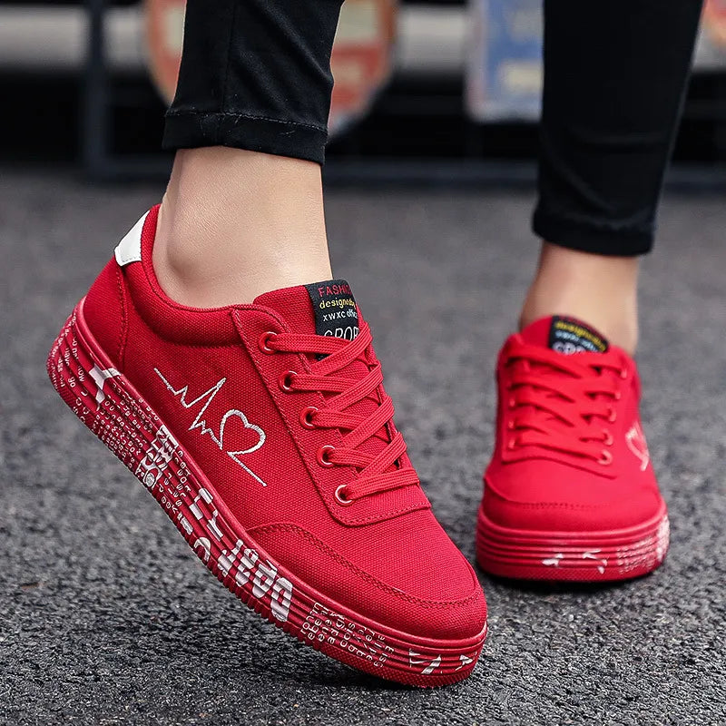 Red canvas sneakers with heartbeat and heart graphic, white sole detail.