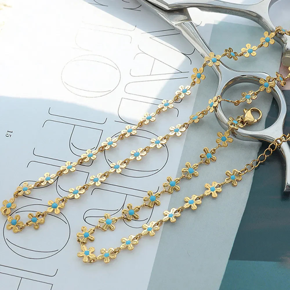 Gold daisy chain bracelet with turquoise enamel centers, 18K gold-plated.