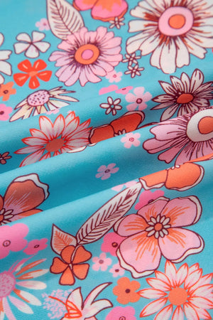 Maxi dress with vibrant bohemian floral print in pink, orange, and white on a blue background.