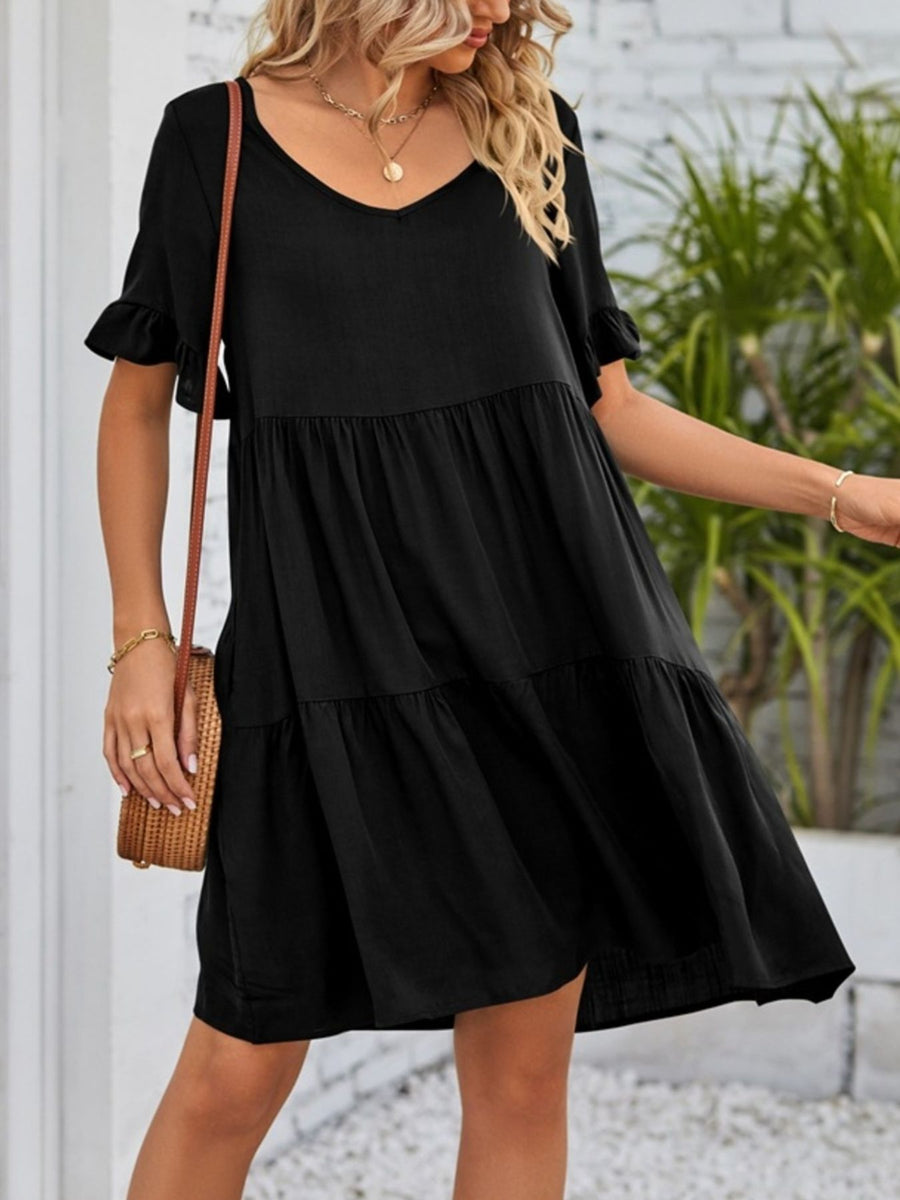 Black tiered mini dress with ruffled sleeves and V-neckline.