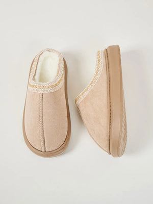 Tan shearling house slippers with embroidered trim and faux suede upper.