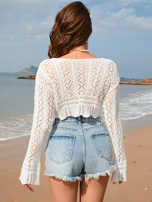 White cropped crochet shrug with diamond pattern and bell sleeves, styled with denim shorts.