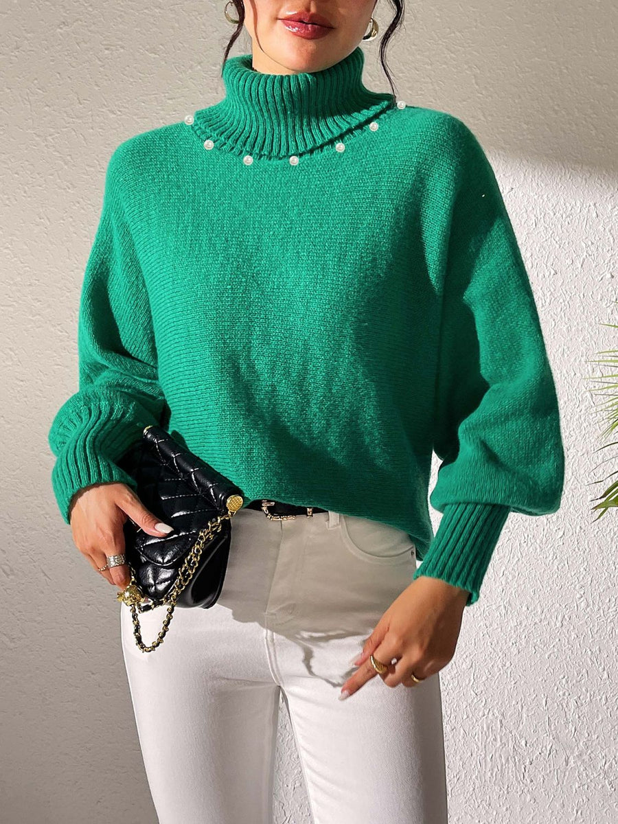 Green turtleneck sweater with dolman sleeves and pearl embellishments at the neckline.