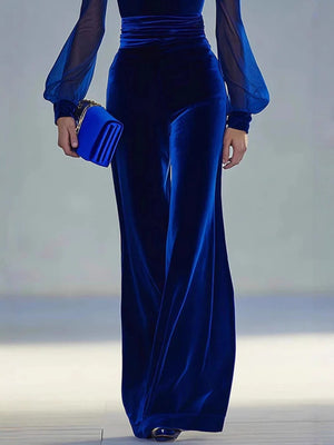 Royal blue velvet wide-leg jumpsuit with sheer balloon sleeves and a matching clutch.