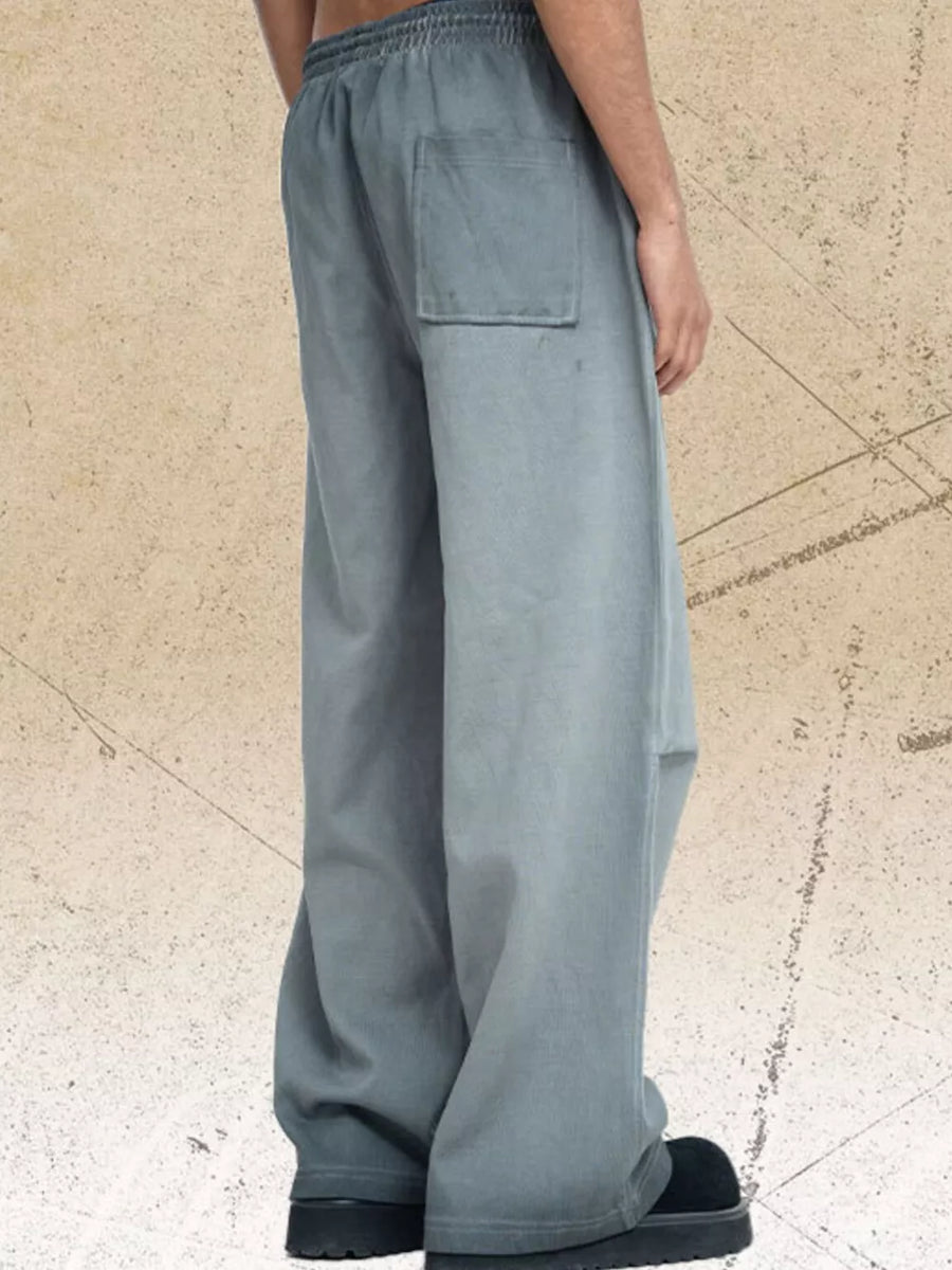 Men's grey wide-leg sweatpants with a back pocket and elastic waistband.