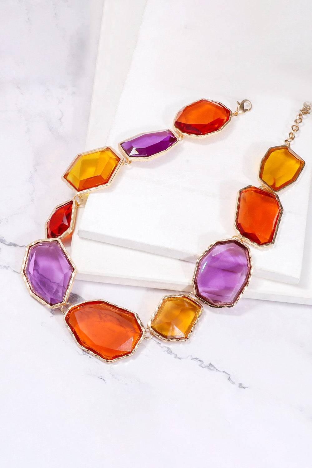 Prismatic resin stone collar necklace with multicolor faceted stones and gold alloy chain.
