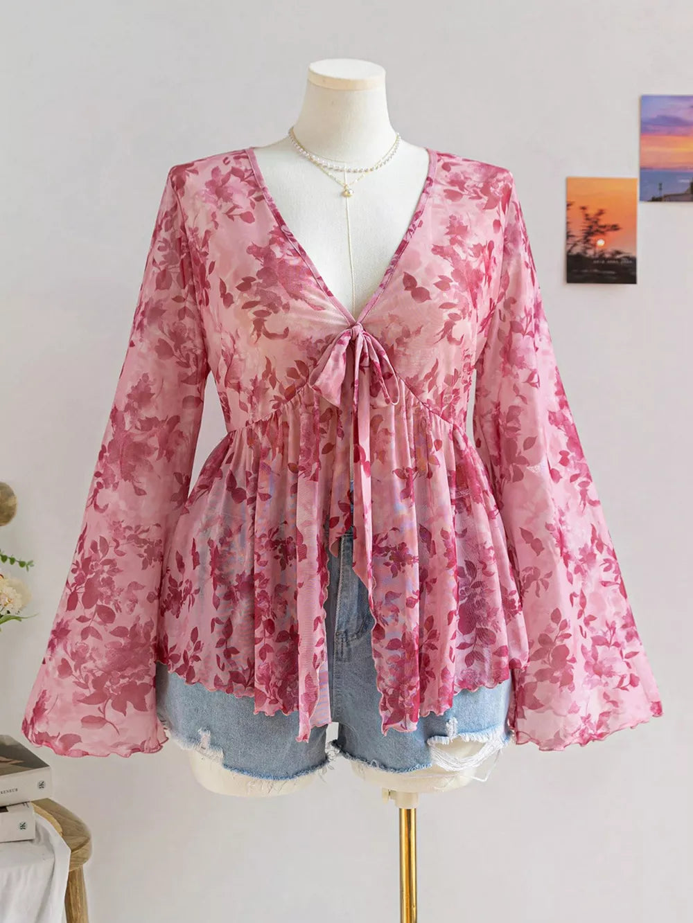 Pink floral chiffon blouse with v-neck and tied detail, bell sleeves.