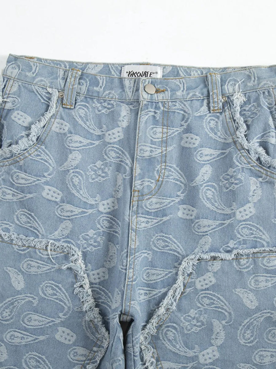Light blue bootcut jeans with allover white paisley pattern and distressed frayed pockets.