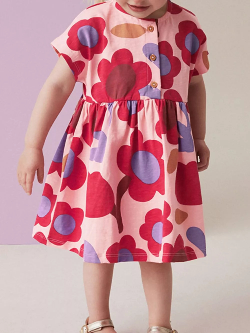 Toddler pink cotton a-line dress with playful red and purple floral print and button-down front.