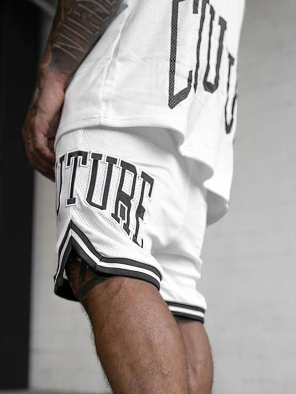 White mesh athletic shorts with black trim and "Couture" graphic detail