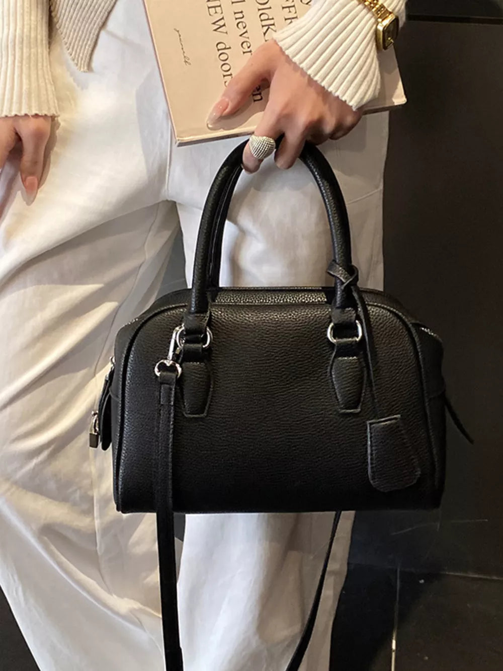 crossbody bag in black featuring top handles and boxy fit