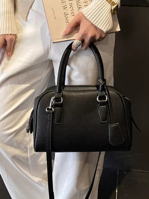 crossbody bag in black featuring top handles and boxy fit