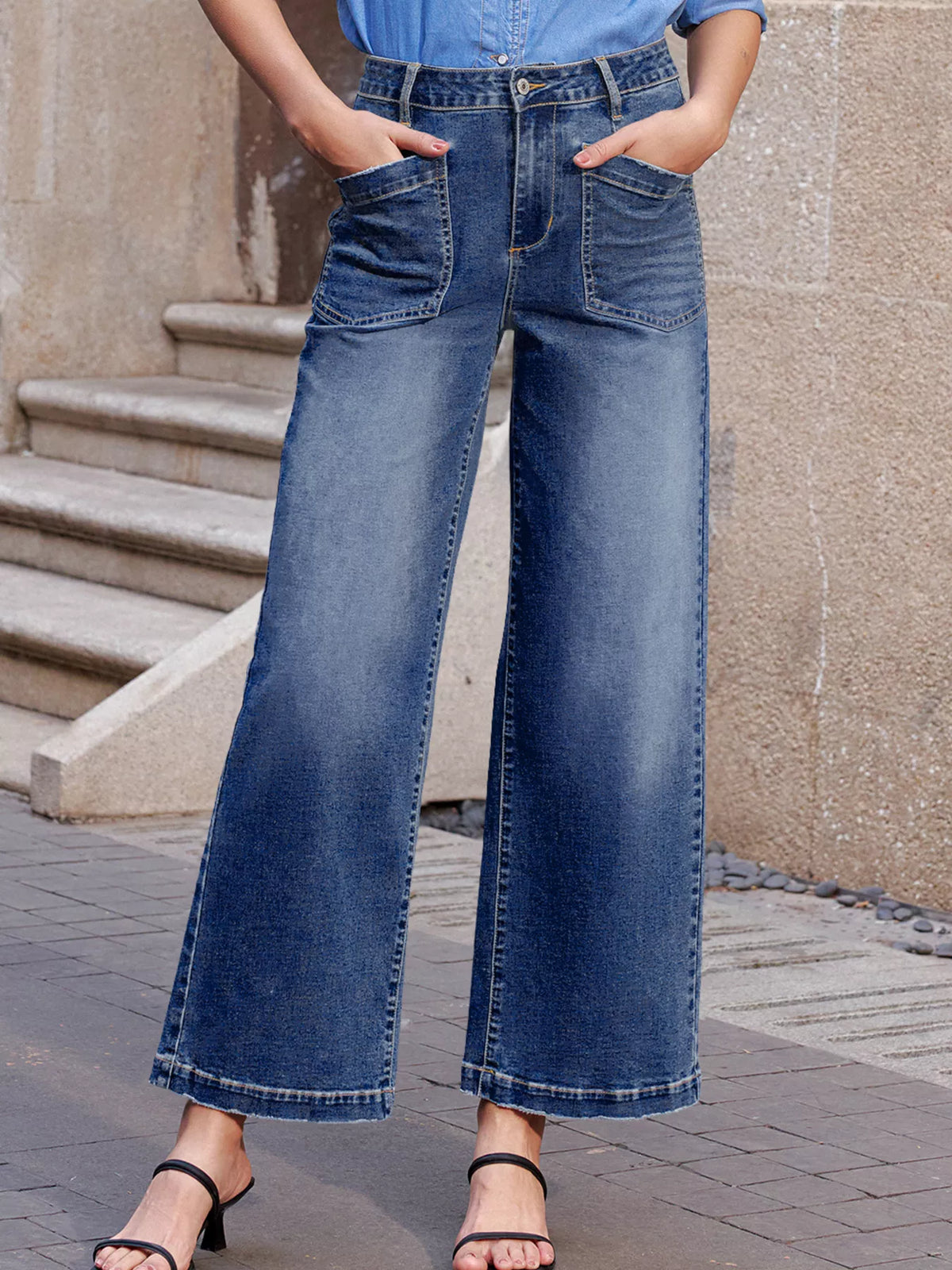 Medium wash denim wide-leg jeans with large patch pockets and frayed hems.