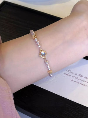 Delicate pearl bracelet with clover charm and gold accents
