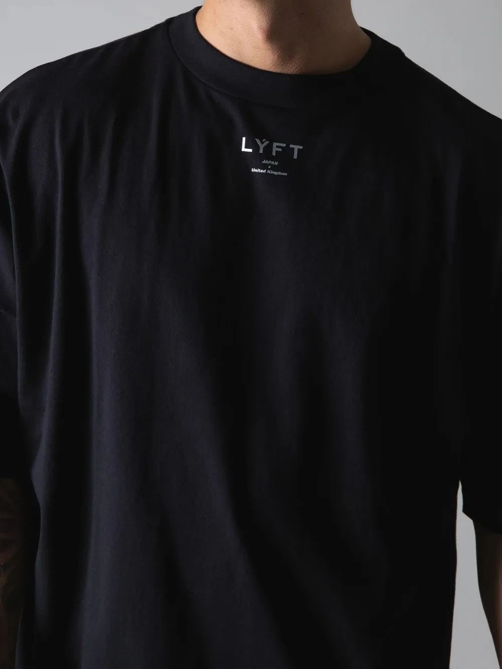 Black oversized graphic tee with silver text detail on chest.