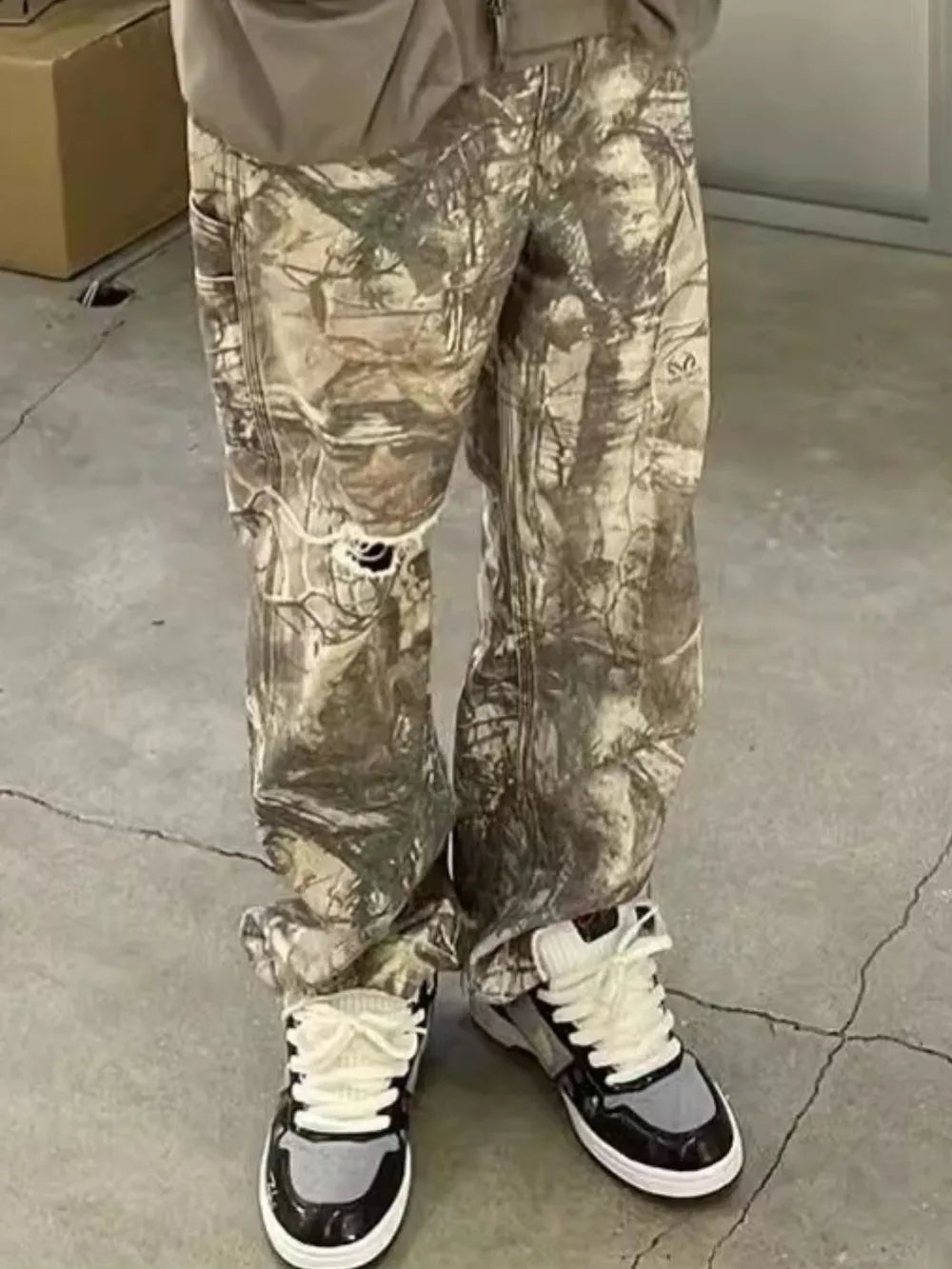Distressed camo carpenter jeans in gray with ripped knees and a relaxed fit.