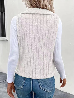 White fleece vest with vertical ribbing and a collared neckline, worn over a white long-sleeve shirt.