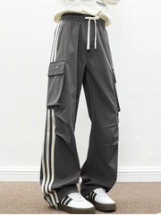 Oversized dark gray cargo pants with white side stripes and flap pockets.