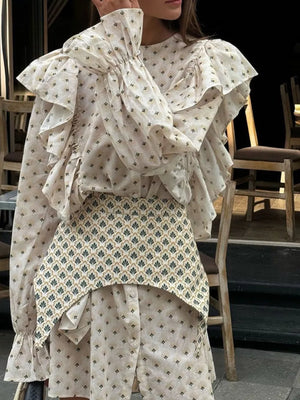 Cream patterned blouse with ruffled sleeves and a contrasting patterned peplum skirt.