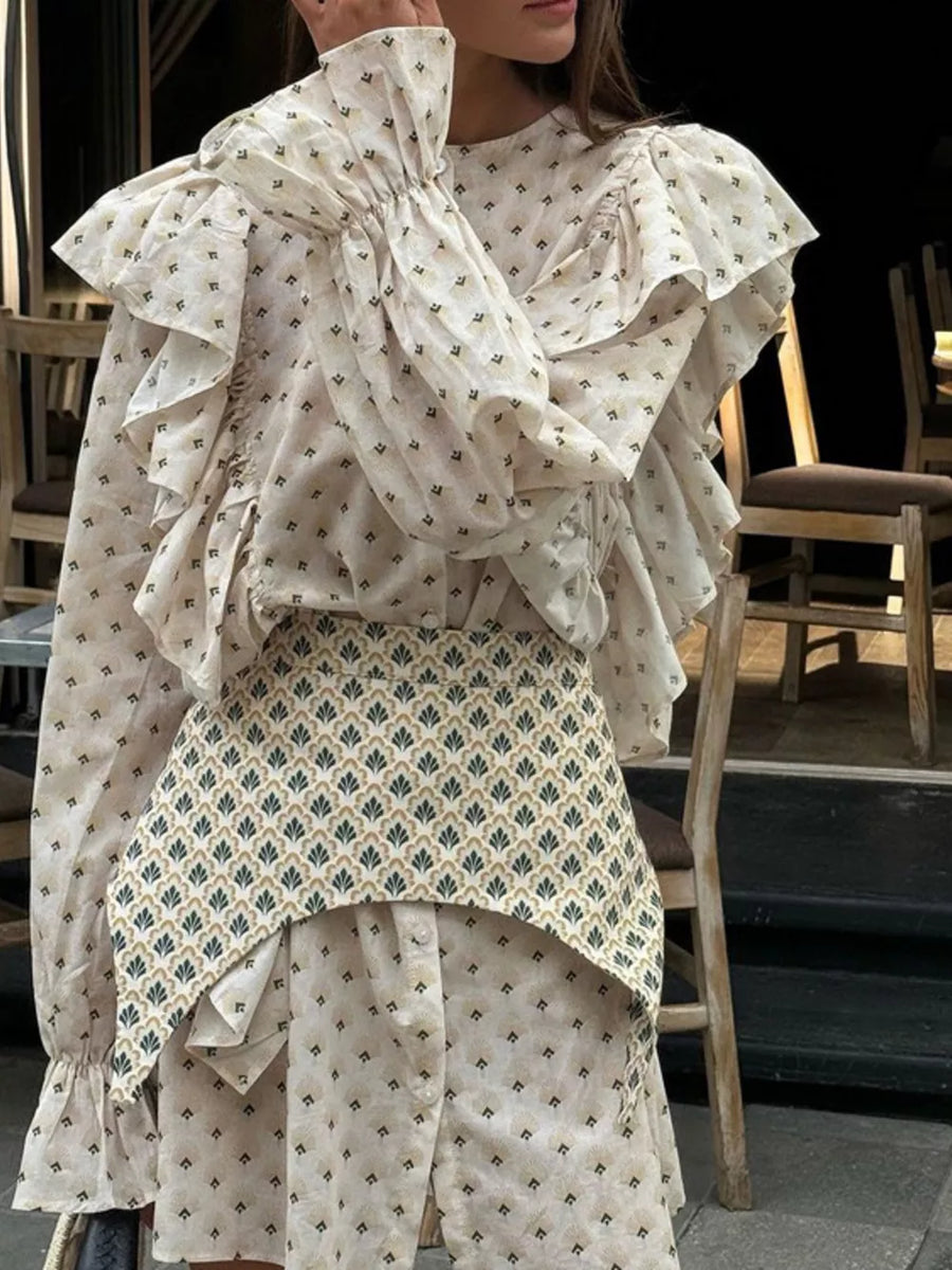 Cream patterned blouse with ruffled sleeves and a contrasting patterned peplum skirt.