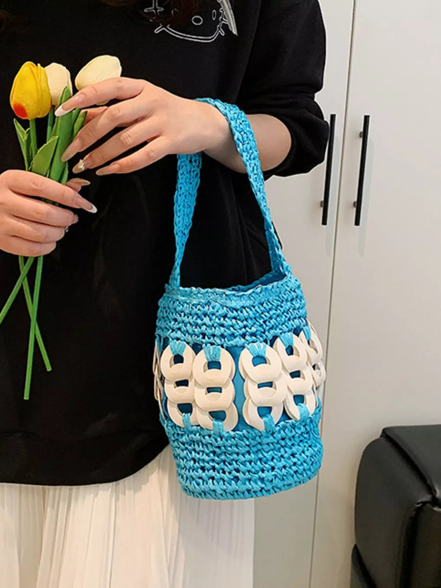 Blue woven straw bucket tote with white ring details and braided strap.
