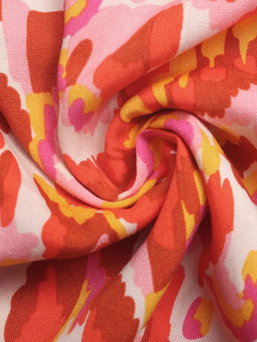 Abstract print V-neck maxi dress in colorful floral pattern with pink, orange, and yellow hues.