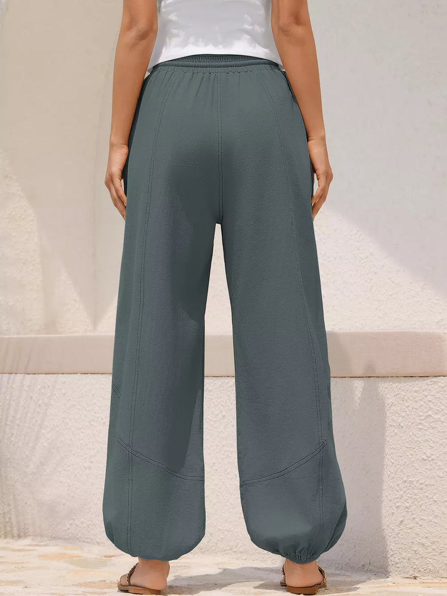 Grey relaxed harem pants with drawstring detail and contrast stitching.