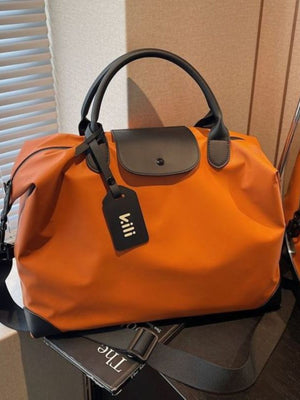 Orange duffel bag with black trim and handles, featuring a detachable luggage tag.