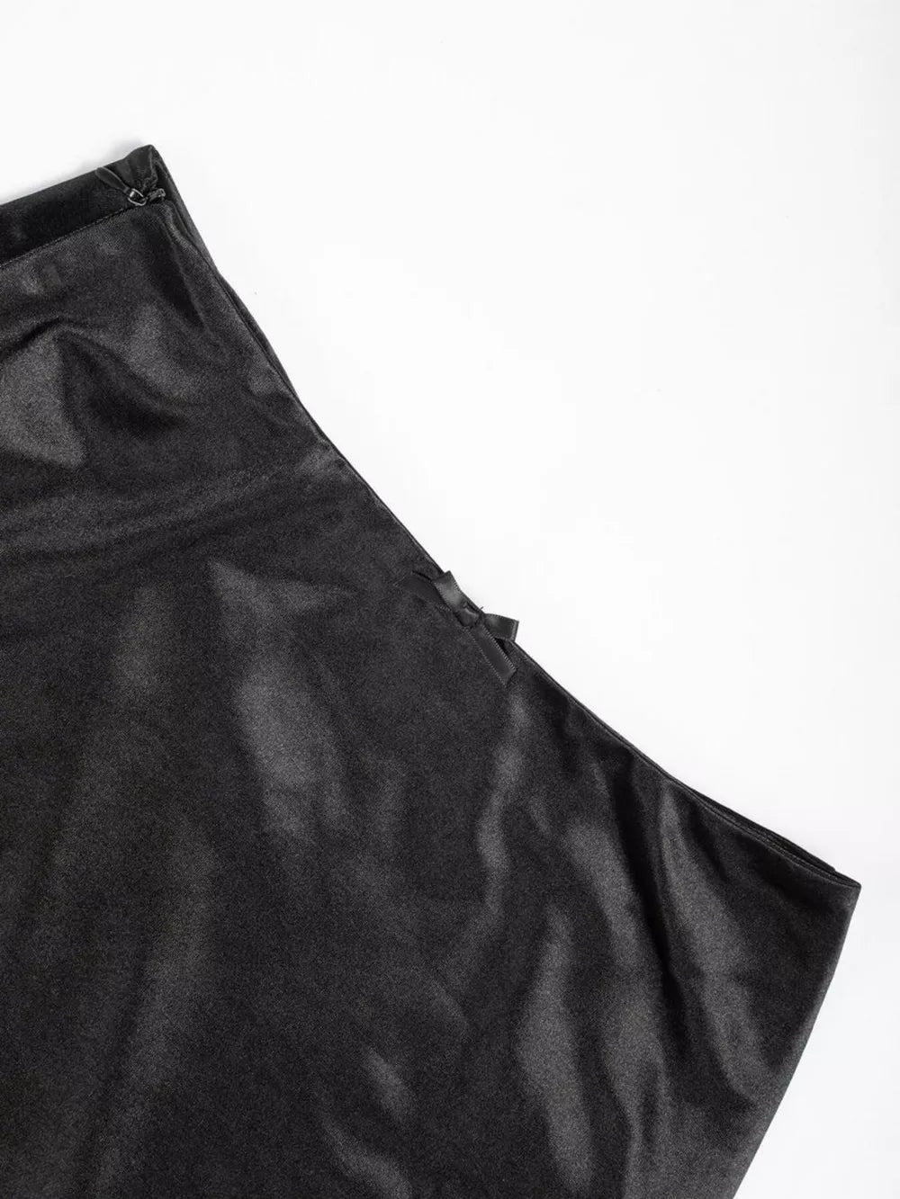 Black satin high-waisted skirt with a subtle bow detail and zipper closure.