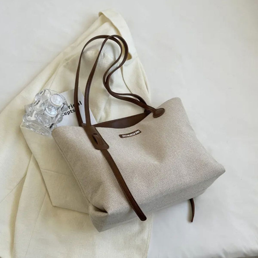 Large canvas shoulder bag with leather trim and straps in coffee color.