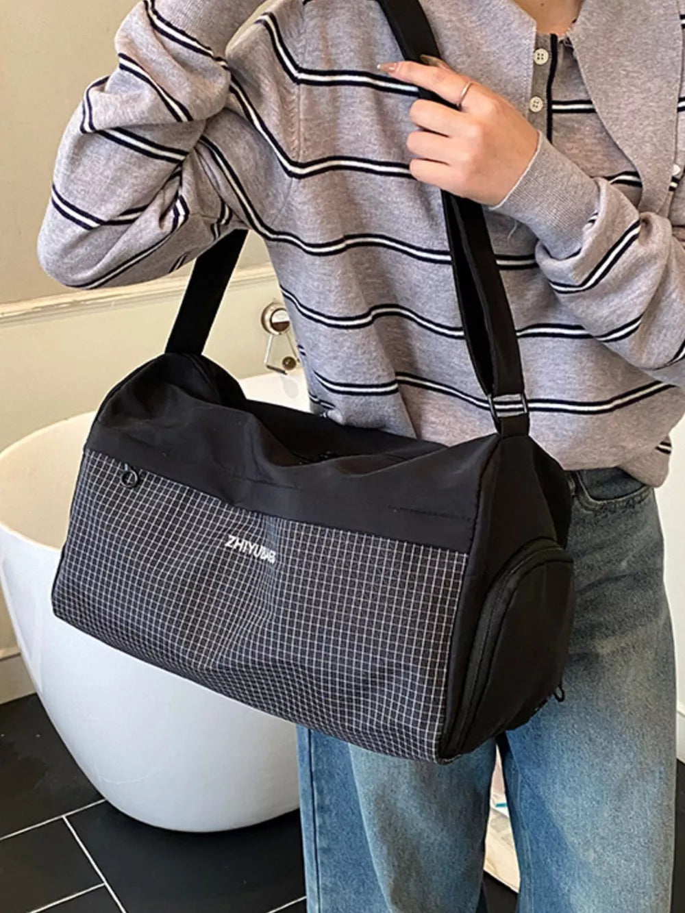 Black travel organizer bag with a subtle grid pattern and white text detail.