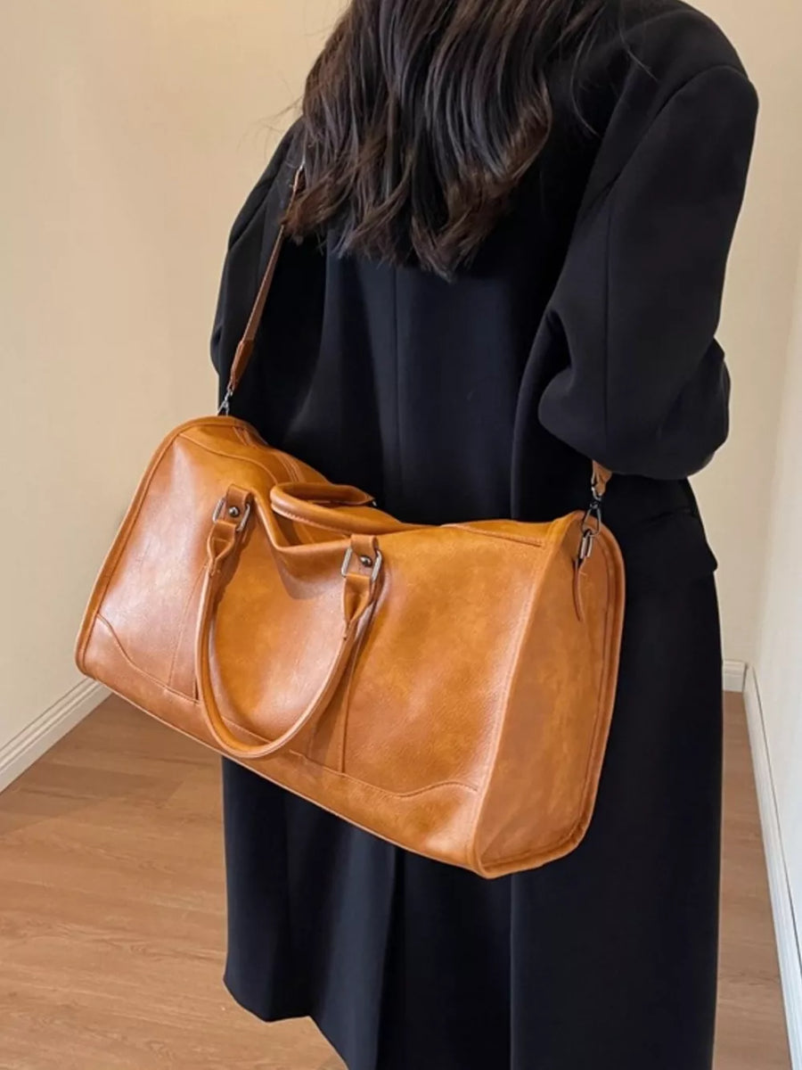 Cognac vintage leather duffle bag with top handles and shoulder strap.