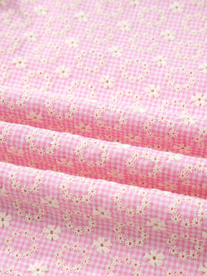 Pink gingham cotton blouse with eyelet floral embroidery and flutter sleeves.