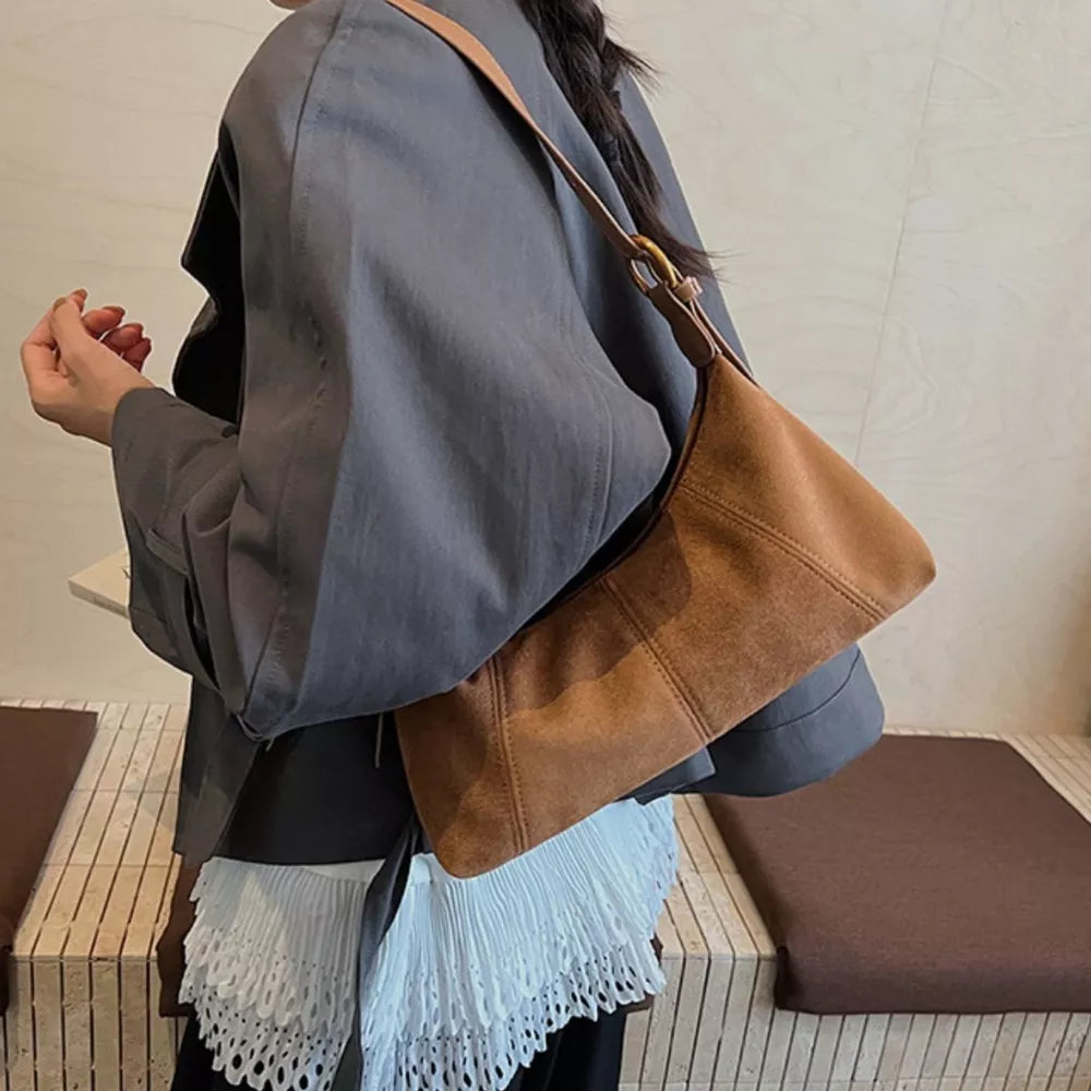 Chic suede crescent shoulder bag in coffee brown with adjustable strap.