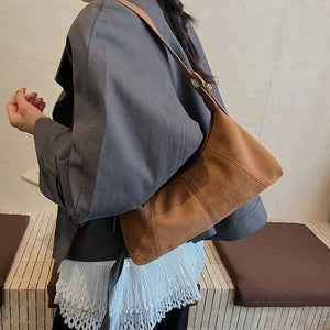 Chic suede crescent shoulder bag in coffee brown with adjustable strap.