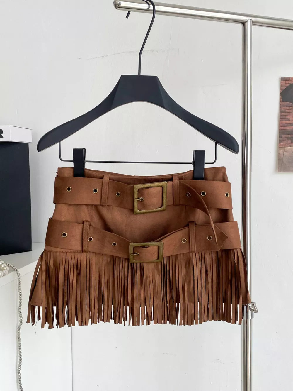 Belted mini skirt in brown suede with double buckle belts and fringe trim.