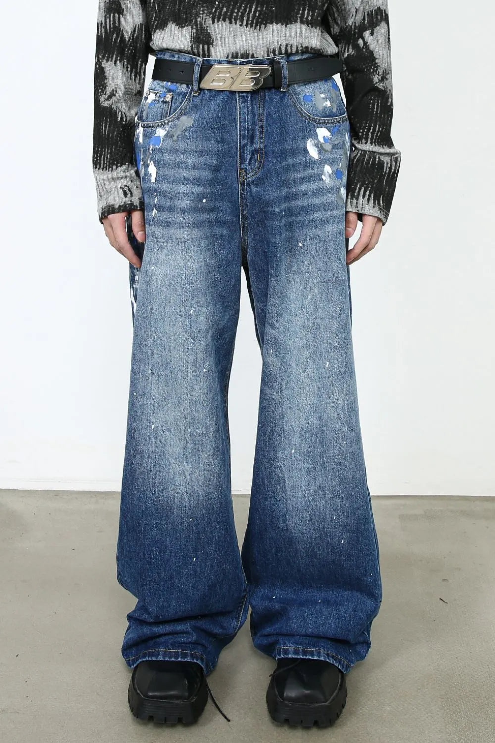 Painterly denim palazzo trousers in medium wash with artistic paint splatters and wide leg.