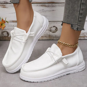 White textured slip-on espadrille sneakers with white laces and a gold chain anklet.