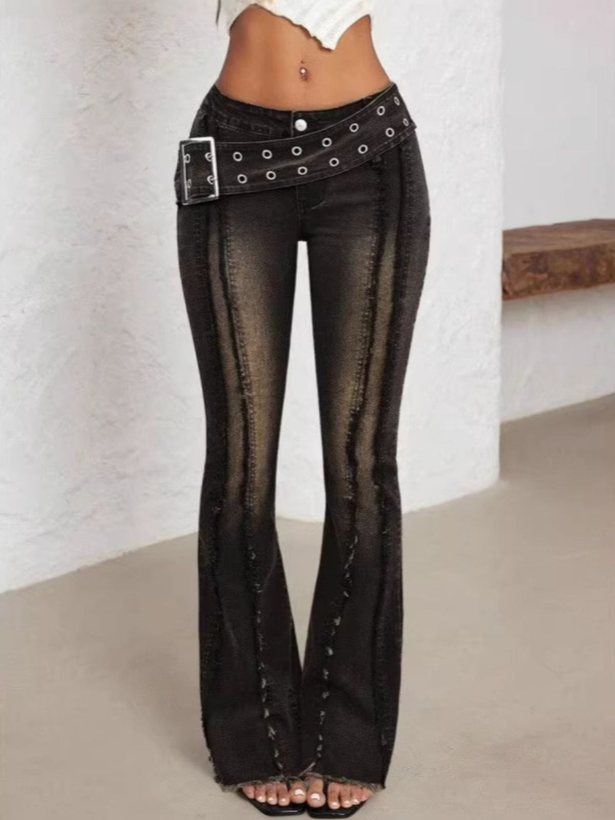 Belted high waist flare jeans in dark wash denim with grommet belt and distressed seams.