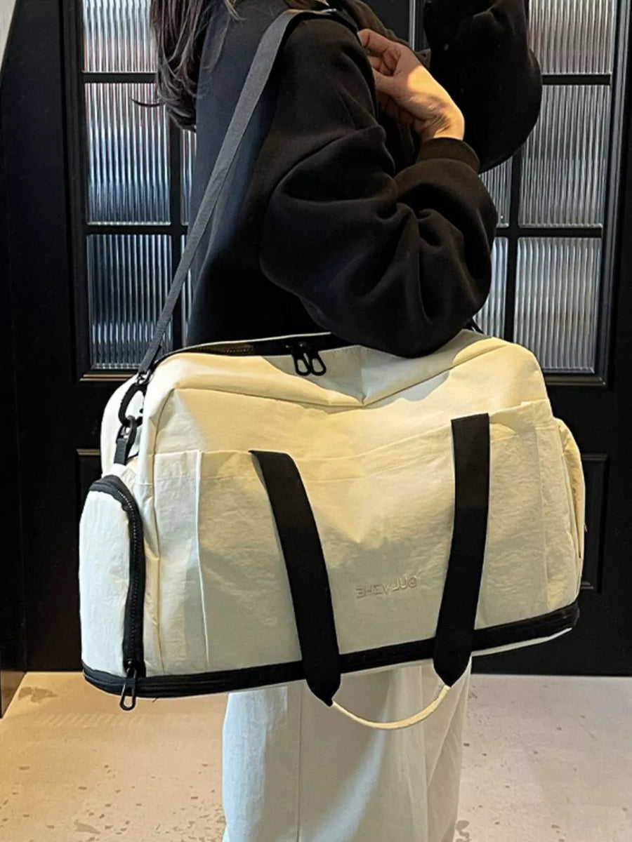Off-white Oxford cloth travel tote bag with black trim and handles, side zip pocket.