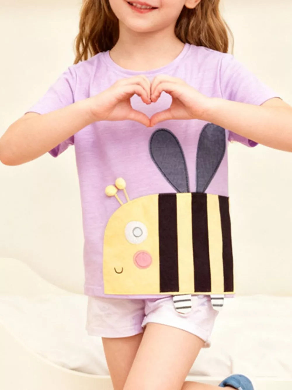 Lavender cotton t-shirt with a yellow and black striped bee applique and grey wings.