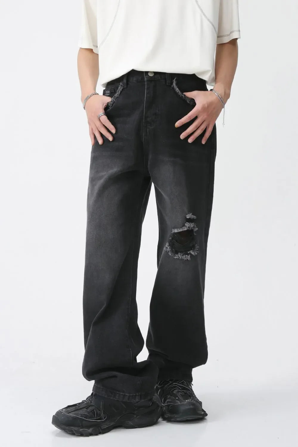 Distressed dark wide-leg denim jeans with raw edges and a knee rip.