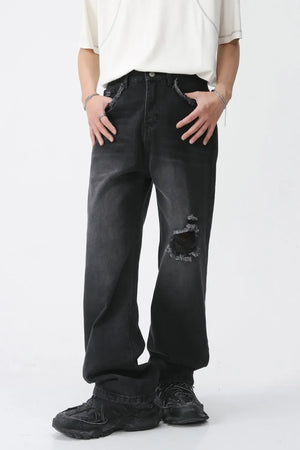 Distressed dark wide-leg denim jeans with raw edges and a knee rip.