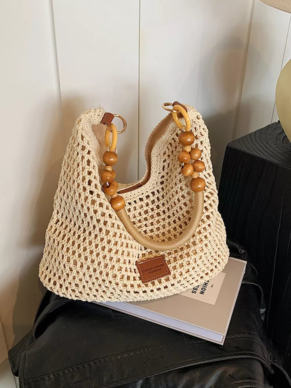 Khaki crochet tote bag with beaded handles and a leather logo patch.