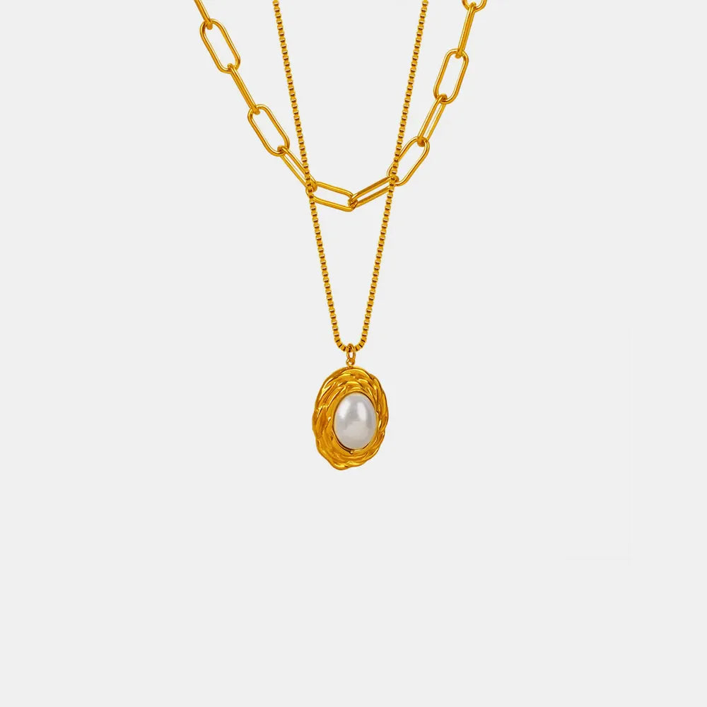 Gold double-layered necklace with oval pearl pendant and textured frame.