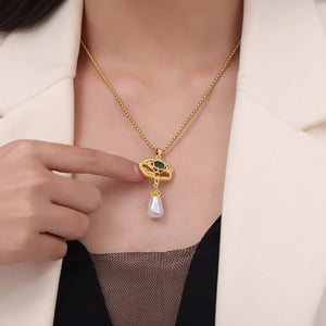 Gold botanical pearl drop pendant necklace with green stone detail.