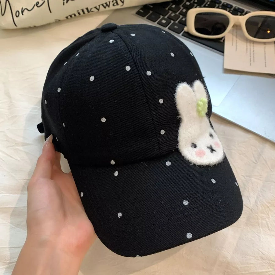 Black polka dot baseball cap with a white bunny applique and green accent.