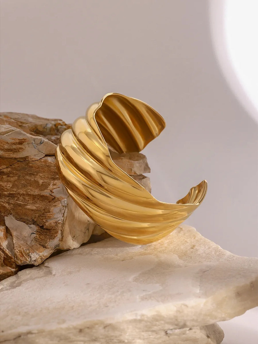 Sculpted wave cuff bracelet in gold, 18K gold-plated, adjustable band with textured detail.